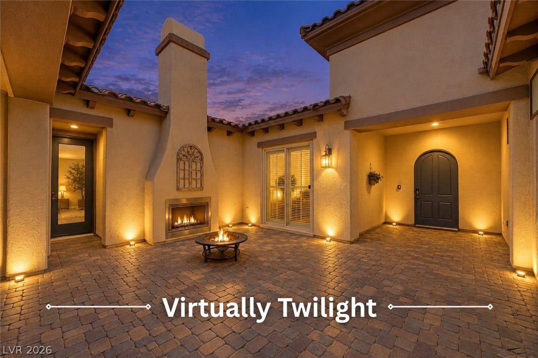 An inviting stone-paved courtyard features a towering outdoor fireplace under twilight skies.
