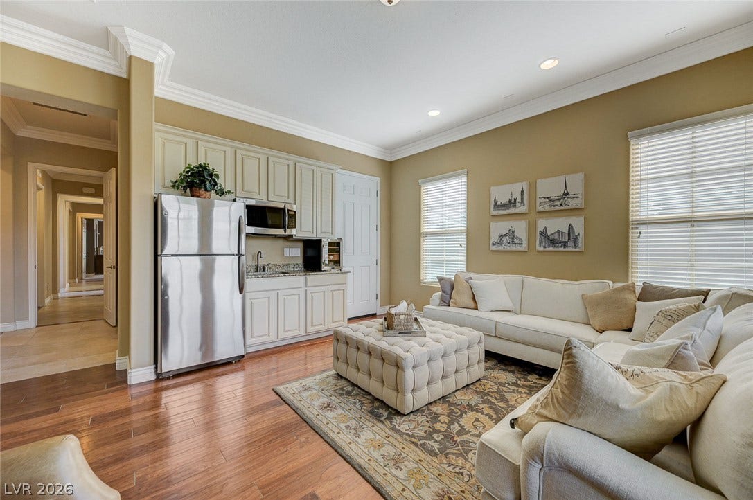 Rich hardwood floors and elegant crown molding elevate this open-concept living area with wet bar.
