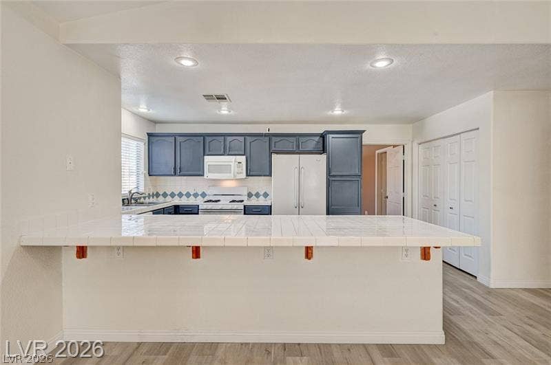3327 Erva Street, #207, Las Vegas, NV 89117 Tiled countertops and recessed lighting define this open kitchen design.