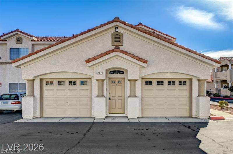 3327 Erva Street, #207, Las Vegas, NV 89117 Spanish tile roofing and twin garage doors accent this stucco exterior under clear blue skies.