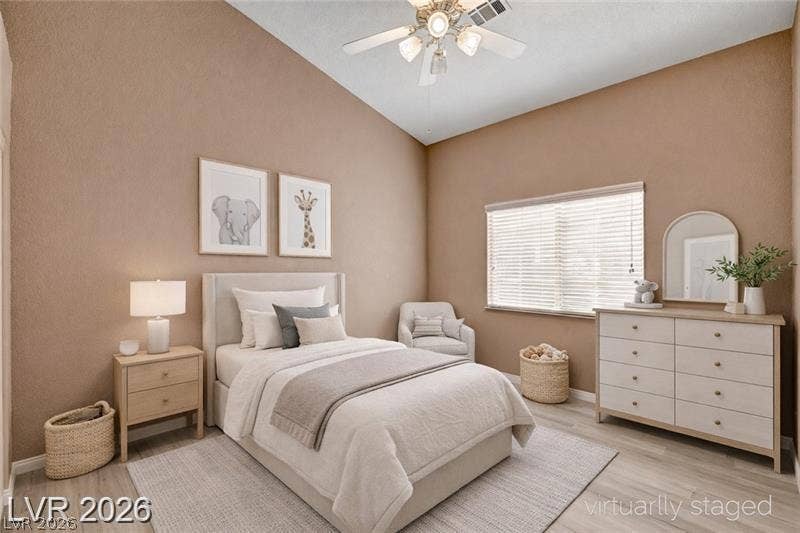 3327 Erva Street, #207, Las Vegas, NV 89117 A spacious bedroom features vaulted ceilings and light wood-tone flooring under a wide window.
