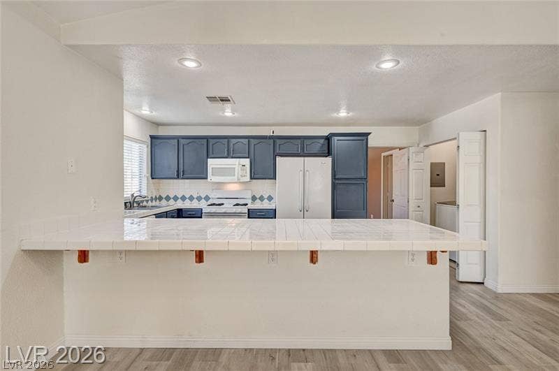3327 Erva Street, #207, Las Vegas, NV 89117 Gleaming tile countertops and dark cabinetry define this functional kitchen layout.