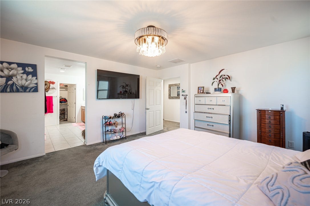 A spacious bedroom provides plush carpeting and direct access to an adjacent private bathroom.