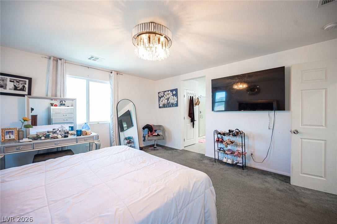 Soft carpeting underfoot and an elegant light fixture define this comfortable main bedroom suite.