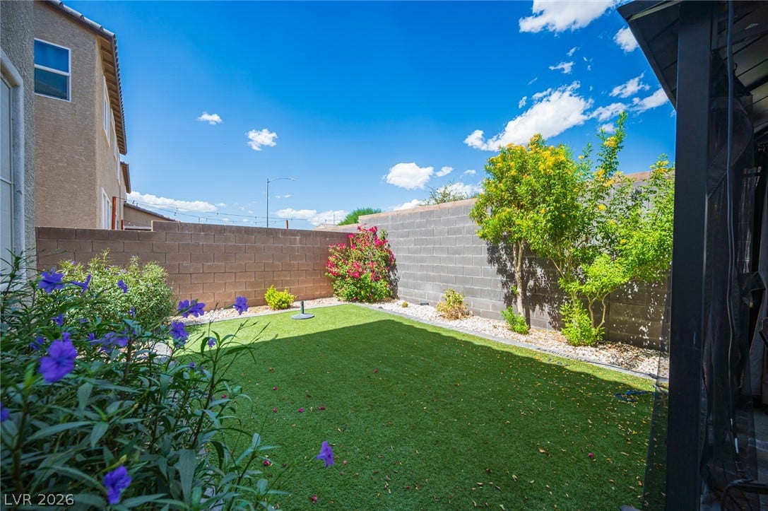 High block walls enclose a private lawn area under clear blue skies.