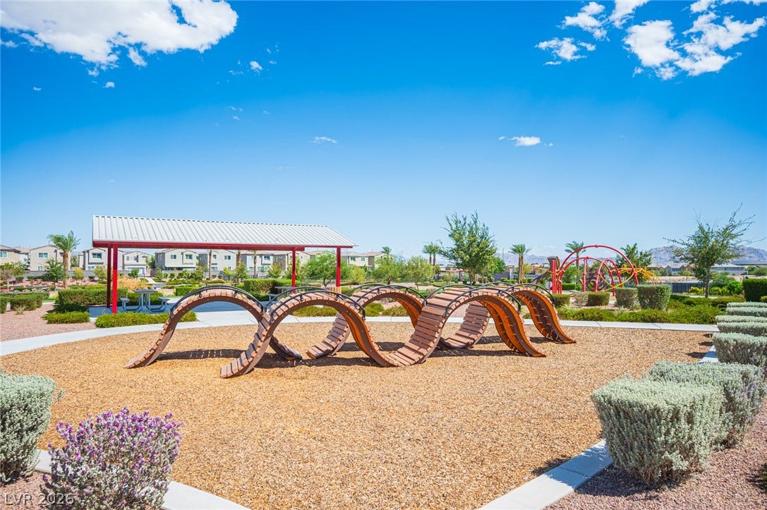 An inviting community playground features modern climbing structures under a clear blue sky.