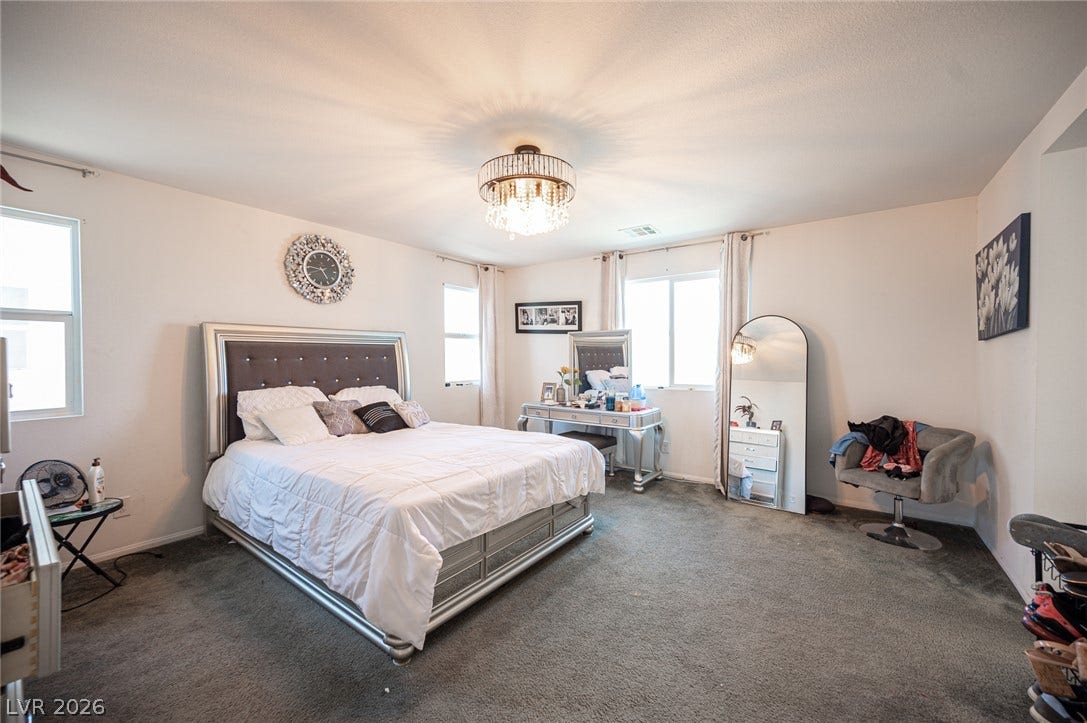 Plush wall-to-wall carpeting and multiple large windows define this spacious main bedroom suite.