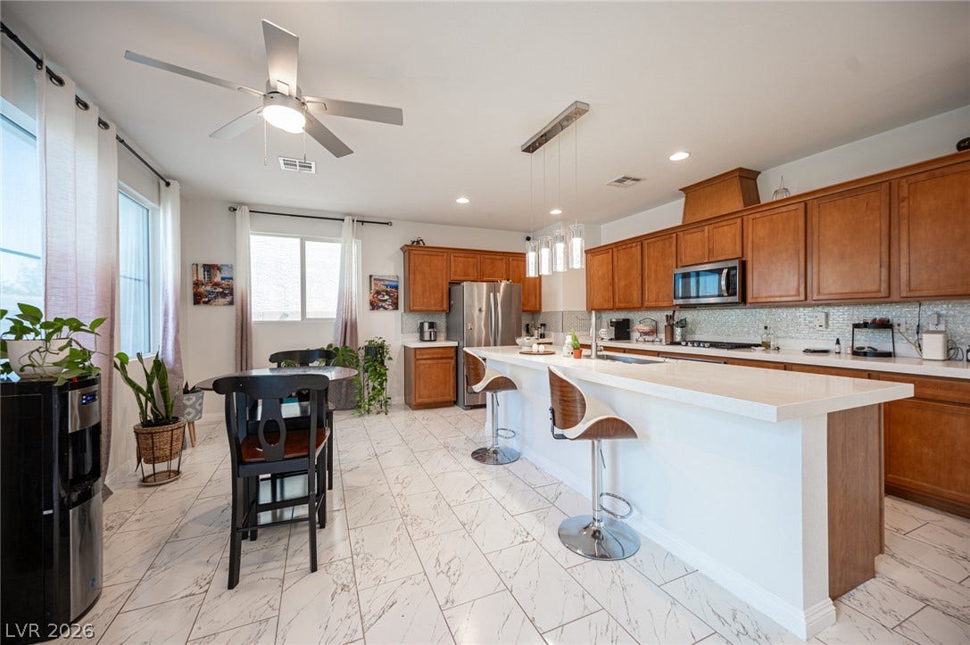 Polished tile flooring flows beneath classic wood cabinetry and a central breakfast island.