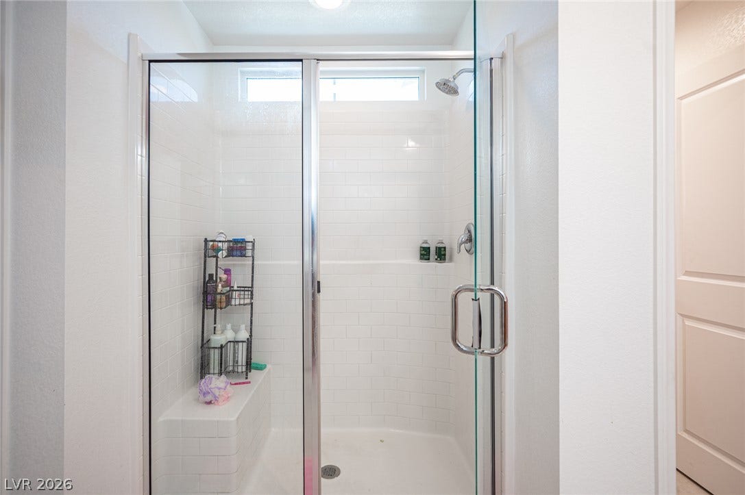 Clean subway tile lines this walk-in shower featuring a built-in bench and glass enclosure.