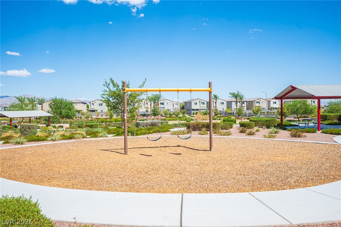 A community park features a playground and covered picnic pavilions set against a mountain backdrop.