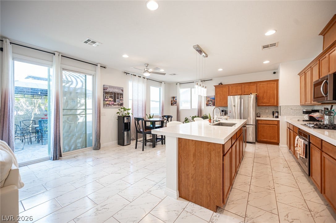 An open layout kitchen flows into a dining area with polished tile flooring throughout.