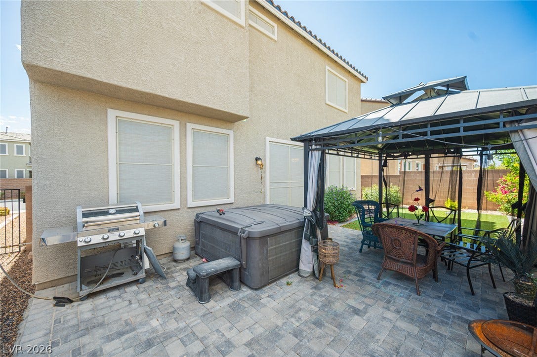 An inviting paver stone patio rests alongside the stucco exterior under clear blue skies.