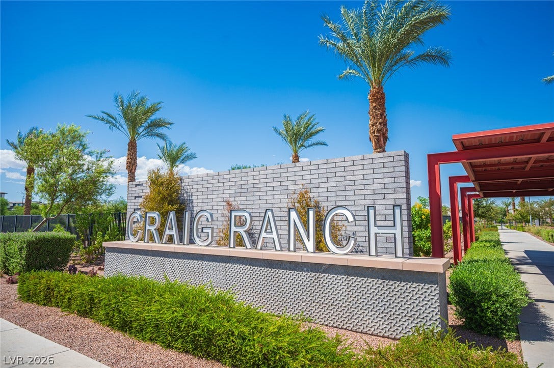 A modern masonry monument sign marks the entrance under clear blue skies.