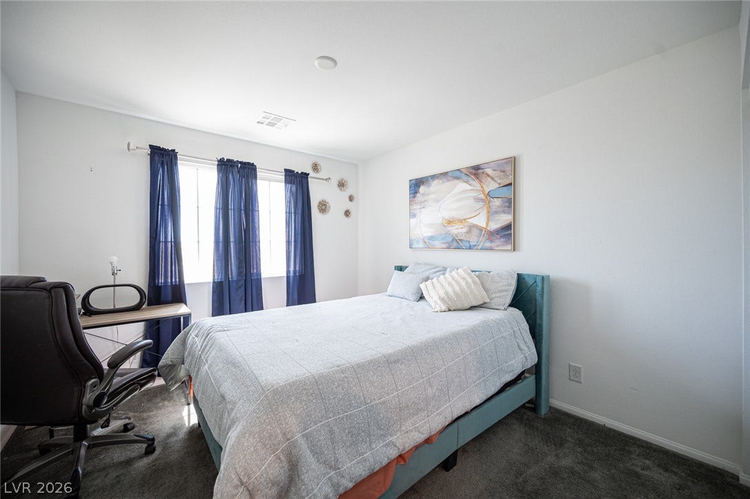 Natural light streams through windows onto plush carpeting in this serene bedroom.