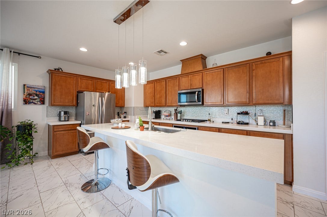 Rich wood cabinetry contrasts beautifully with sleek stone countertops and polished tile flooring.