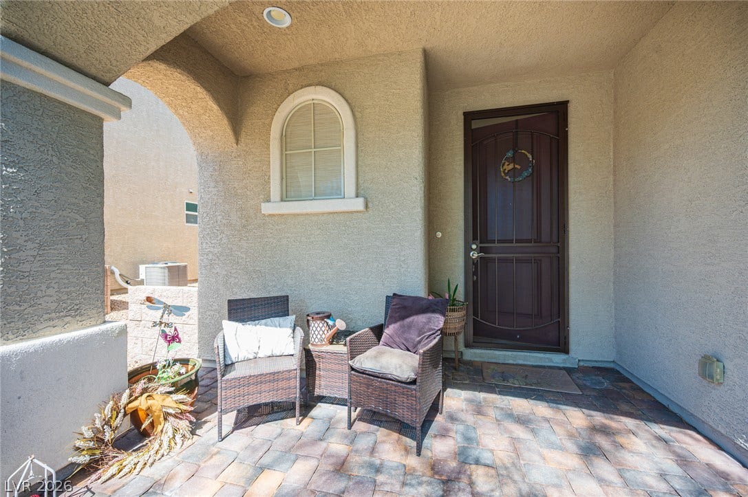 An arched covered entry features interlocking pavers and a classic stucco finish.