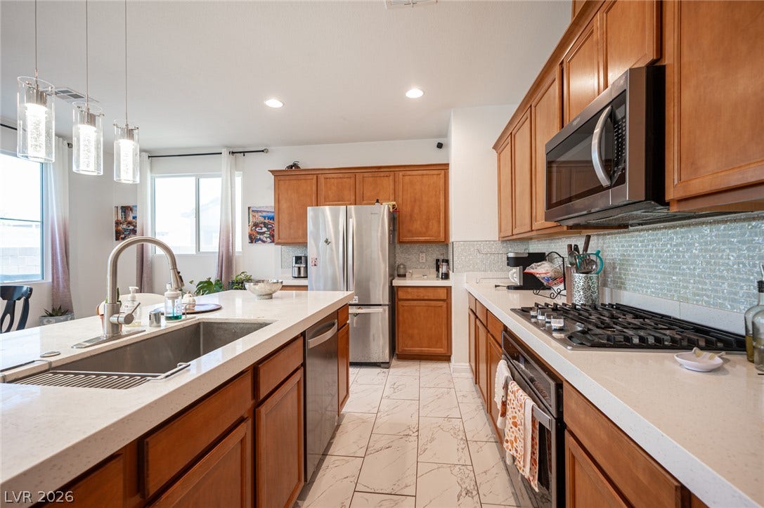 Warm wood cabinetry pairs with stone countertops and a modern tile backsplash in this kitchen.