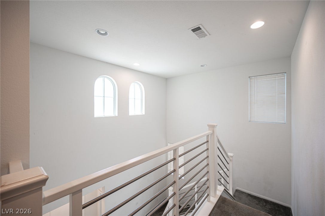 A modern staircase features clean lines, metal railings, recessed lighting, and arched accent windows.