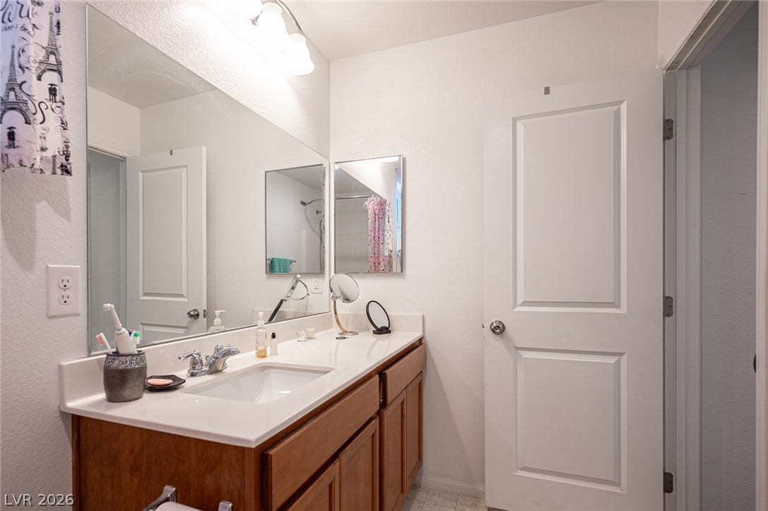 Warm wood cabinetry pairs with a clean white vanity top in this functional bathroom layout.
