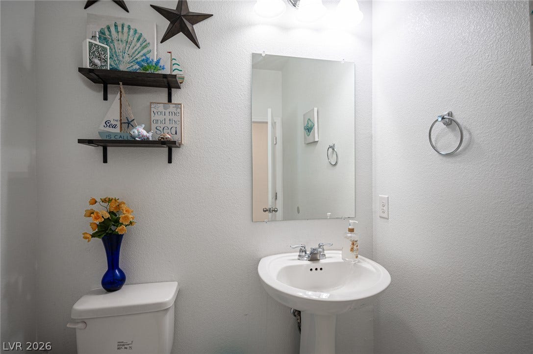A classic pedestal sink sits beneath a simple frameless wall mirror.