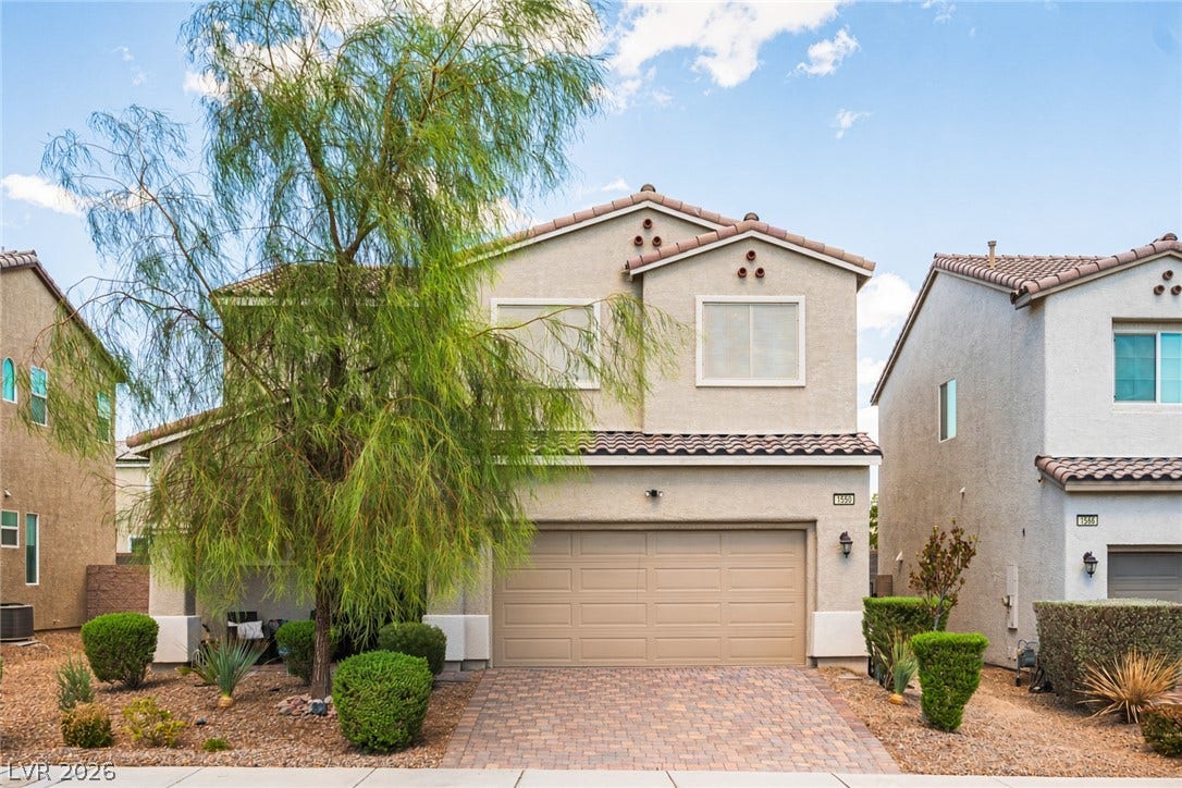 A classic stucco exterior features a tiled roof and a paved driveway leading to the garage.