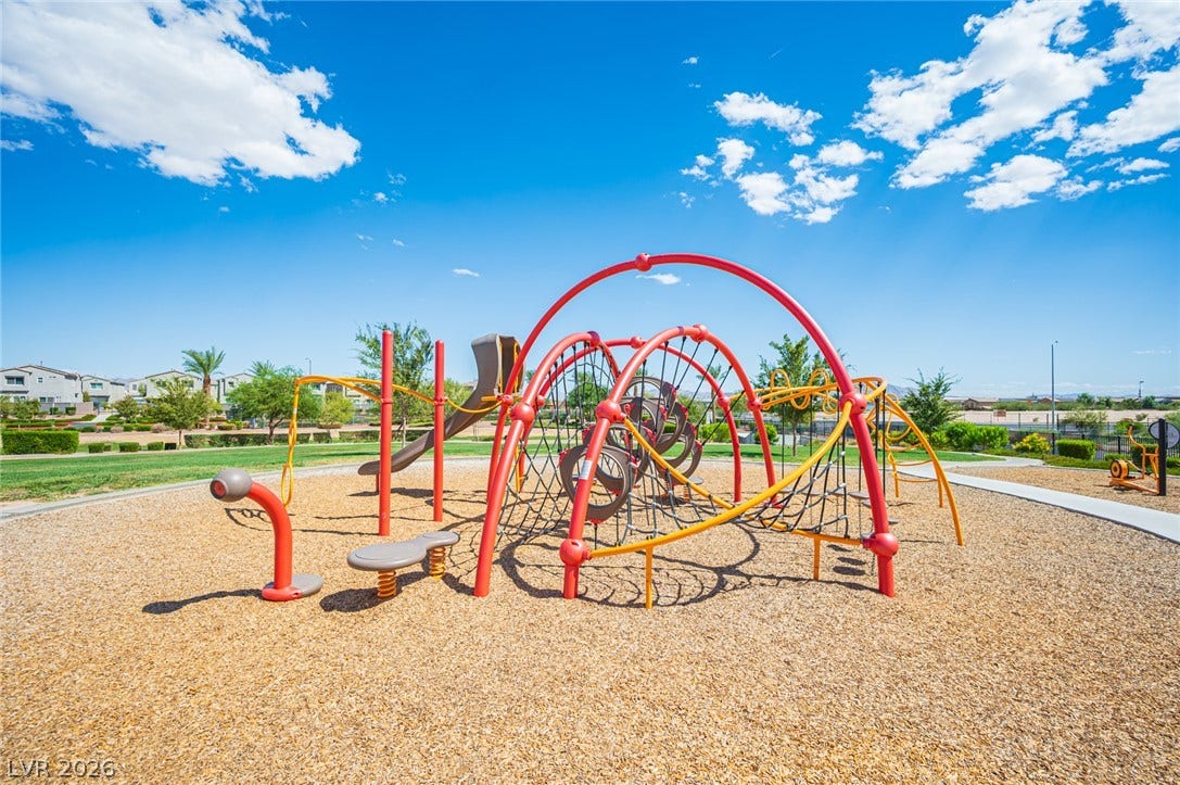 An expansive community playground set against a clear blue sky offers abundant outdoor recreation.