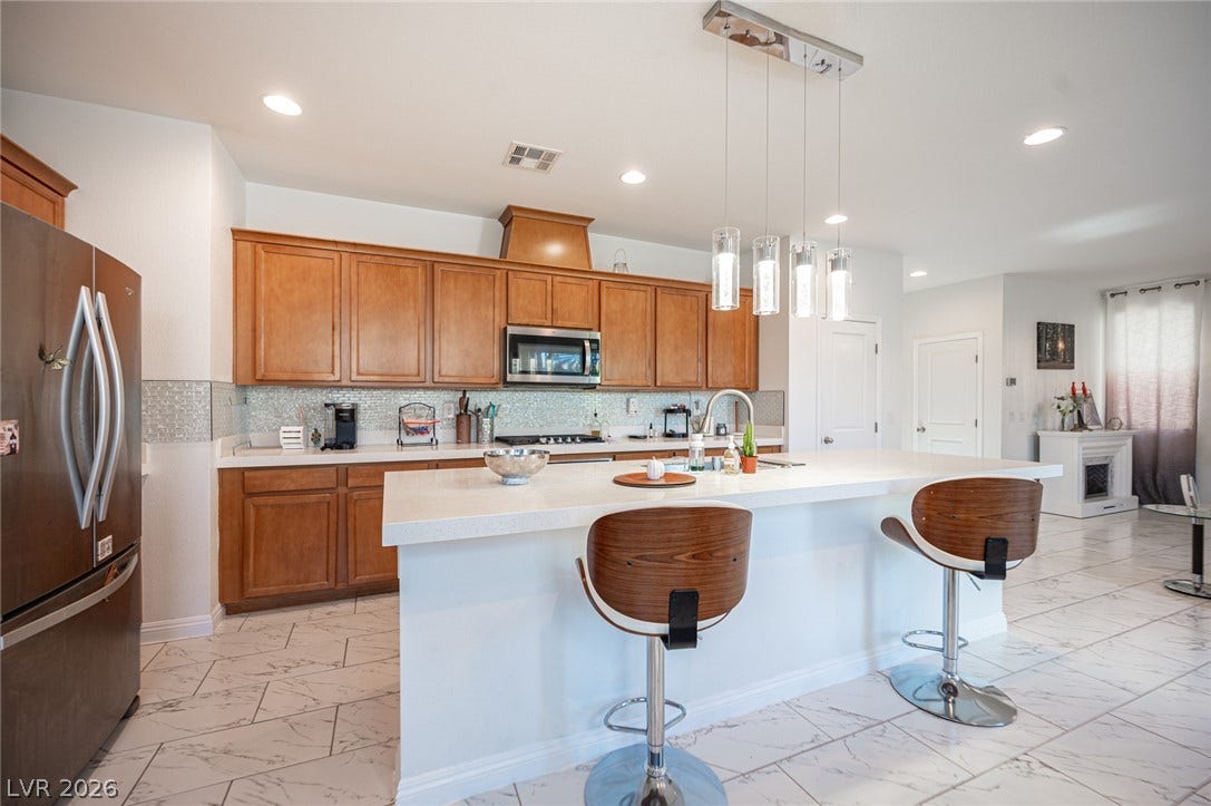 Rich wood cabinetry contrasts beautifully with clean white countertops and polished tile flooring.