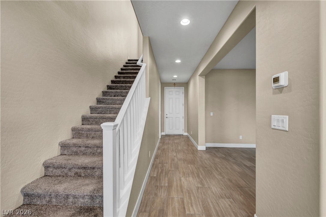 7128 Port Stephens Street, North Las Vegas, NV 89084 Plank flooring and recessed lighting define the welcoming entry corridor and staircase path.