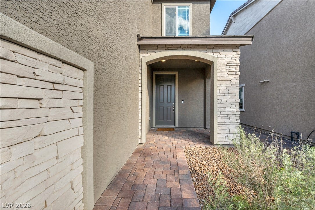 7128 Port Stephens Street, North Las Vegas, NV 89084 A stone-accented arched entryway leads to the front door via a paved walkway.