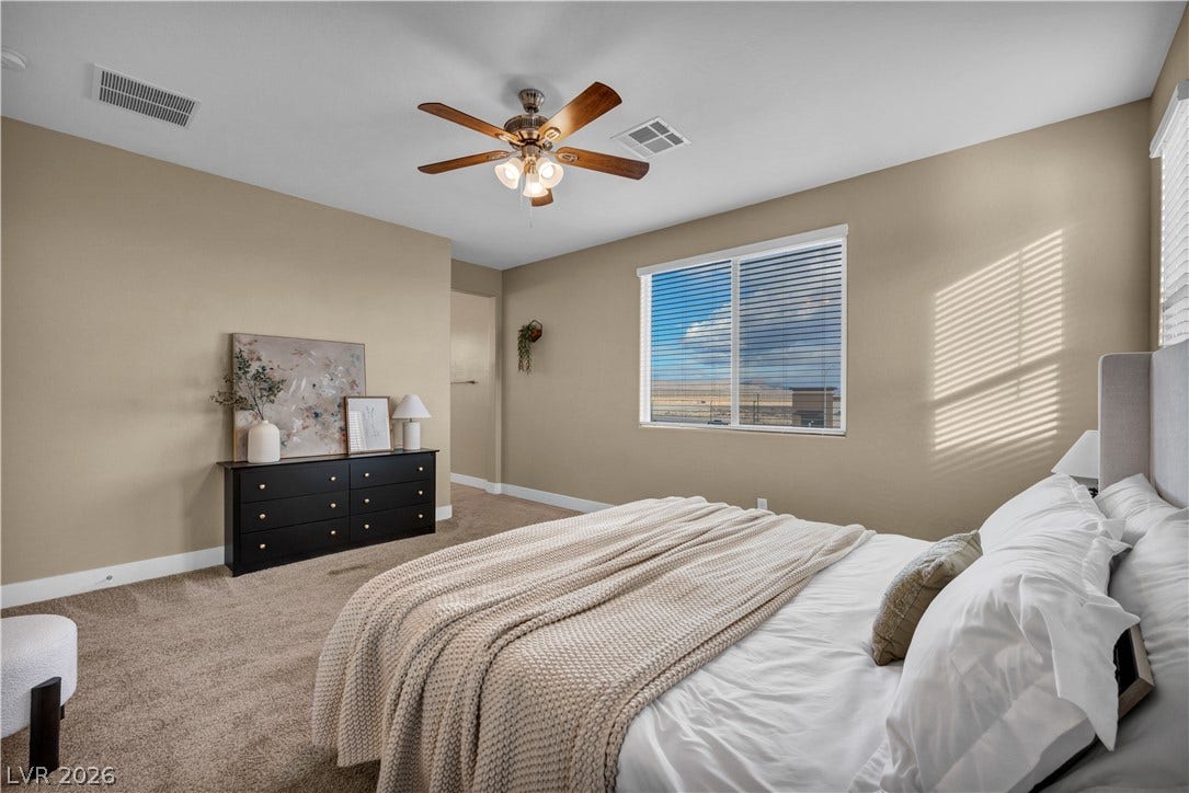 7128 Port Stephens Street, North Las Vegas, NV 89084 Soft carpeting pairs with natural light streaming through the window to create a serene bedroom atmosphere.
