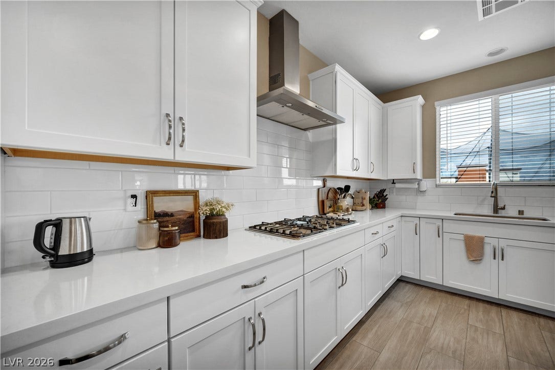 7128 Port Stephens Street, North Las Vegas, NV 89084 Crisp white cabinetry and quartz countertops frame a modern kitchen completed by wood-look tile flooring.