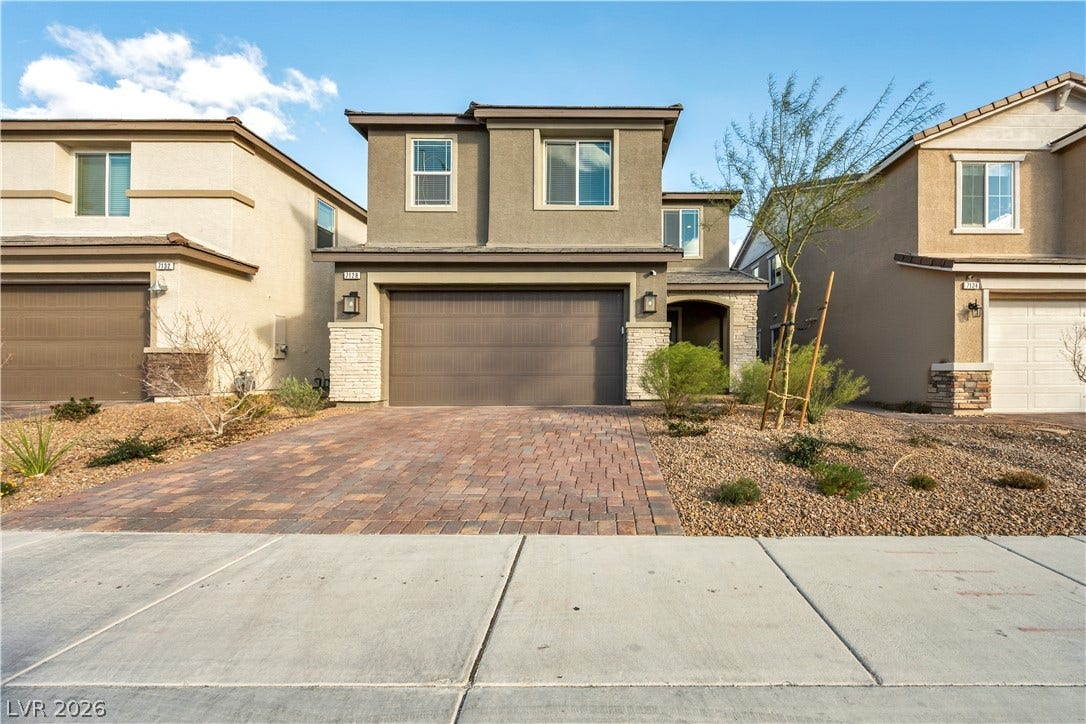 7128 Port Stephens Street, North Las Vegas, NV 89084 A paved brick driveway leads to a modern two-story home with a two-car garage.