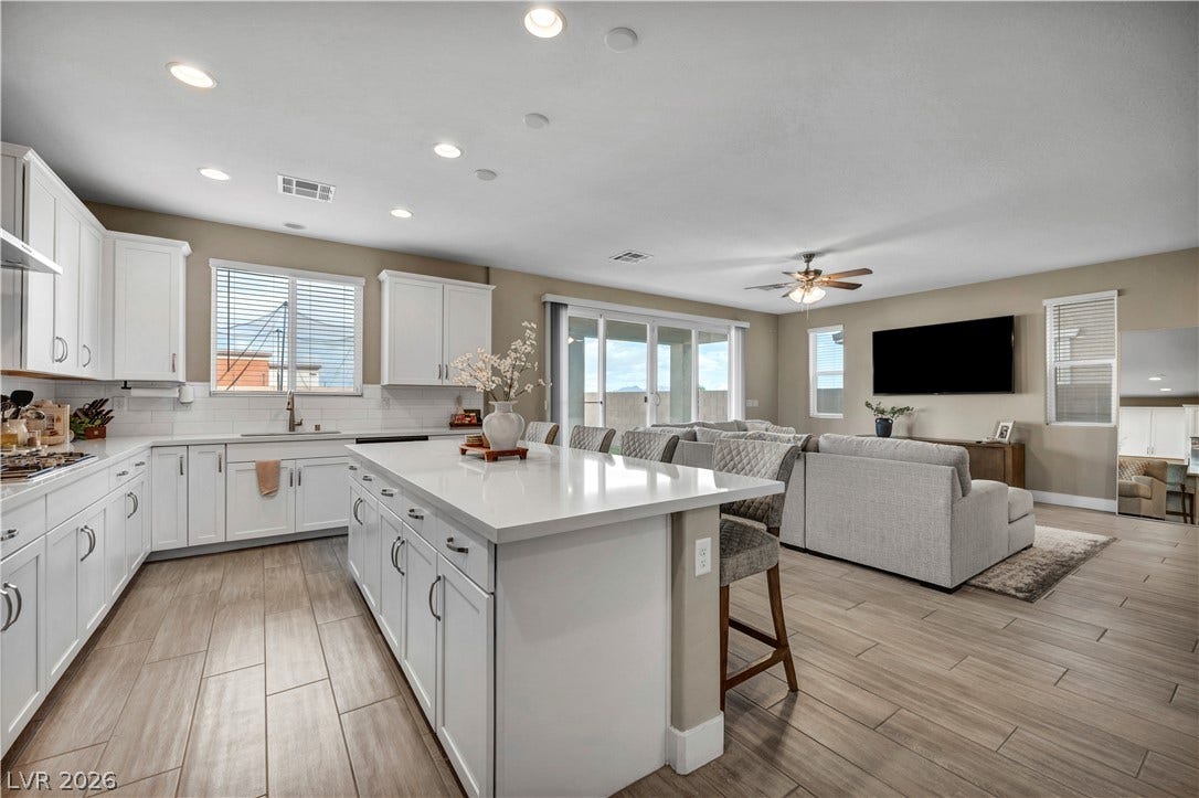 7128 Port Stephens Street, North Las Vegas, NV 89084 Gleaming stone countertops and wood-look tile flooring anchor this expansive open-concept living area.