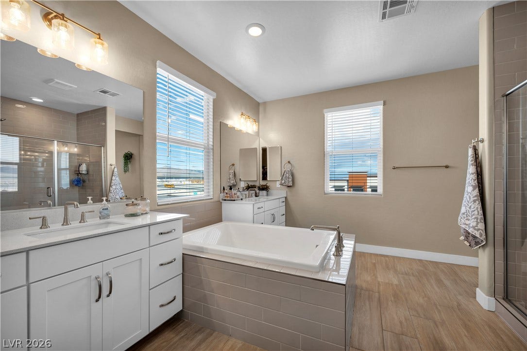 7128 Port Stephens Street, North Las Vegas, NV 89084 A spacious soaking tub anchors this well-appointed bathroom complete with dual vanities and tiled finishes.