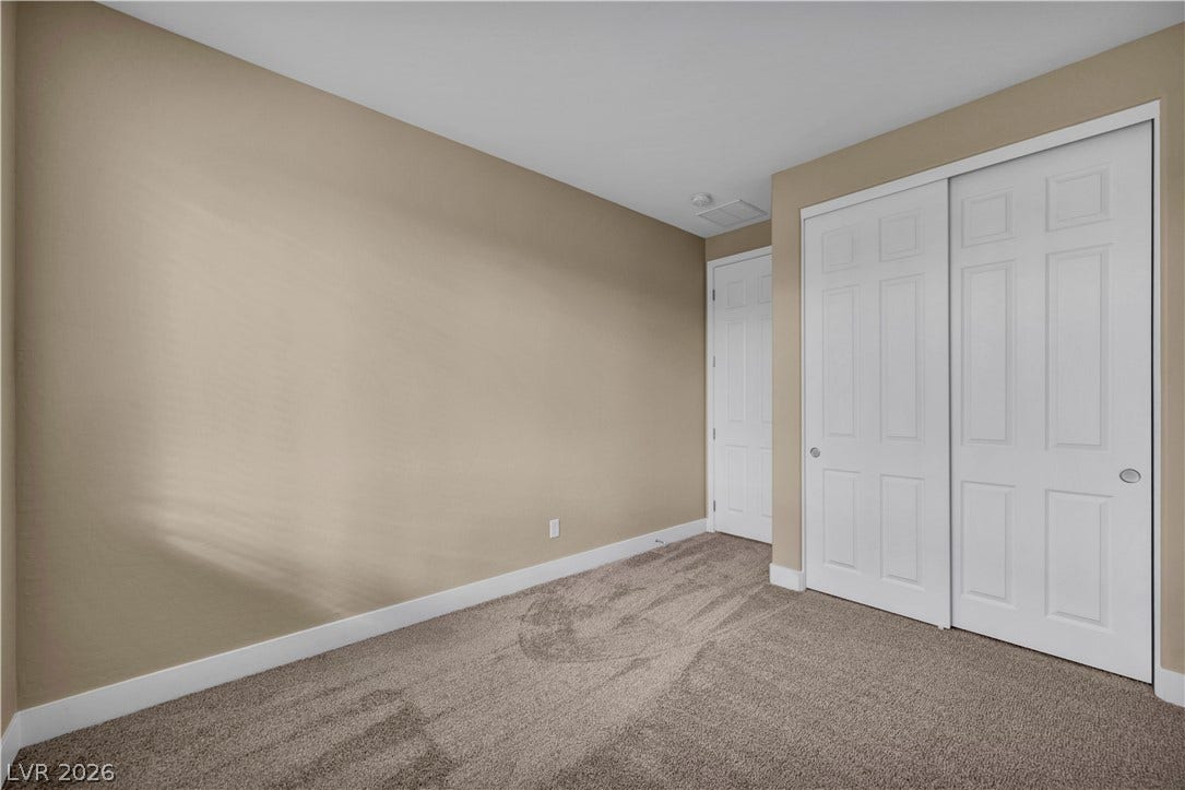 7128 Port Stephens Street, North Las Vegas, NV 89084 Plush carpeting anchors this versatile room featuring a wide closet with classic panel doors.