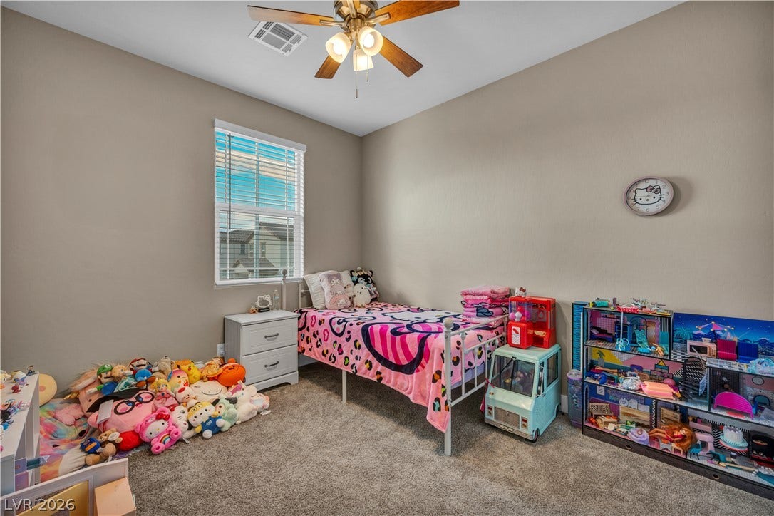 7128 Port Stephens Street, North Las Vegas, NV 89084 A tall window draws natural light across the plush carpeting in this bedroom.