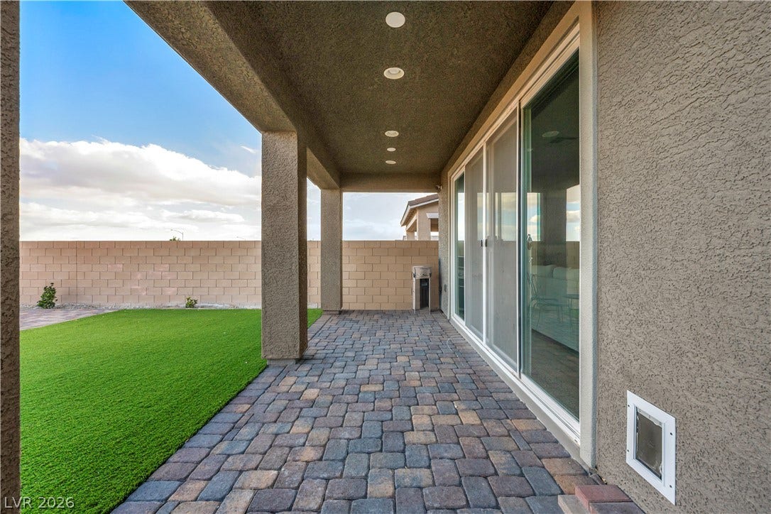 7128 Port Stephens Street, North Las Vegas, NV 89084 A covered paver patio looks out over the manicured backyard lawn and block wall fencing.