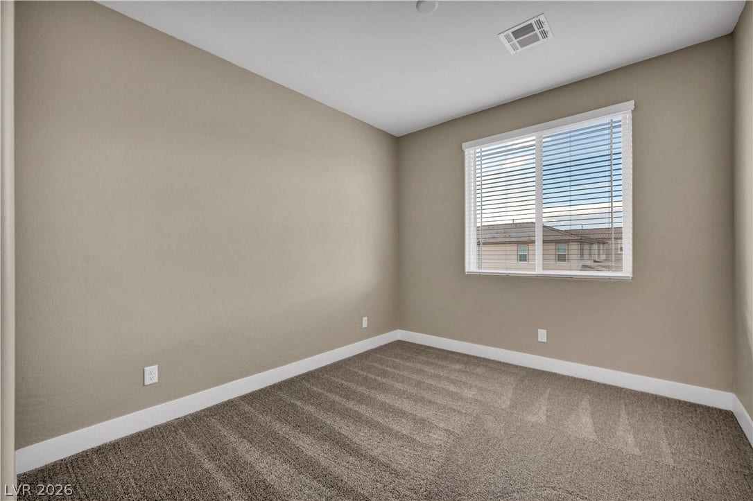 7128 Port Stephens Street, North Las Vegas, NV 89084 A spacious secondary bedroom features plush carpeting and a large window with neighborhood views.