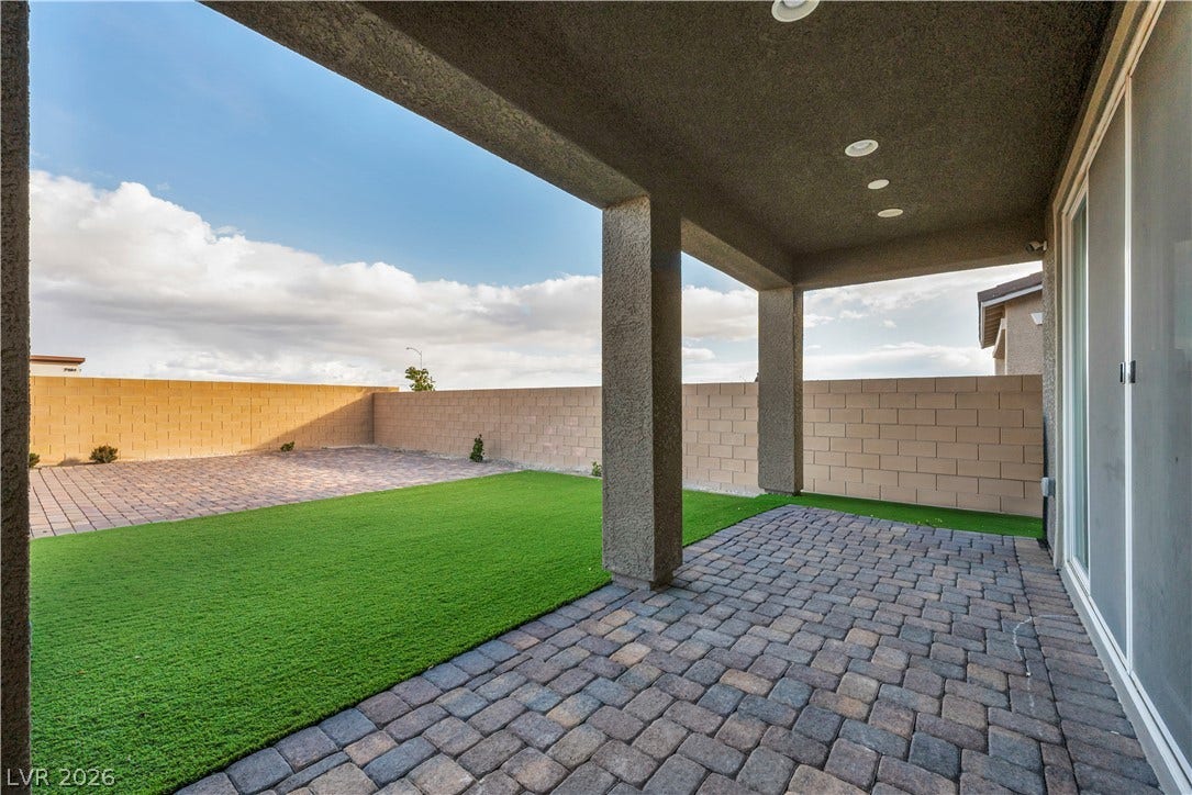 7128 Port Stephens Street, North Las Vegas, NV 89084 A covered patio with brick pavers overlooks a private yard enclosed by masonry fencing.