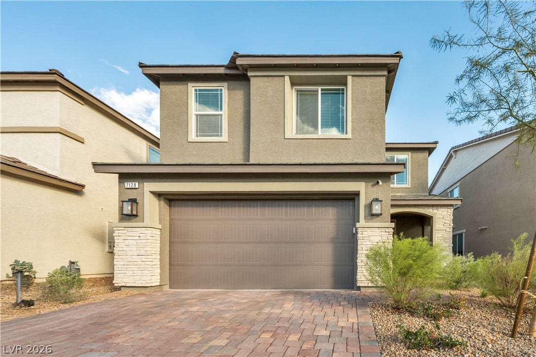 7128 Port Stephens Street, North Las Vegas, NV 89084 Clean lines and stone accents define this modern two-story exterior featuring a paver driveway.