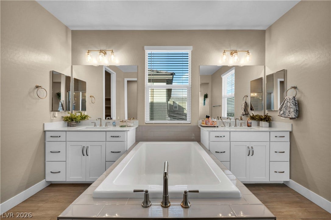 7128 Port Stephens Street, North Las Vegas, NV 89084 A centrally positioned soaking tub anchors dual white vanities in this classic bathroom space.