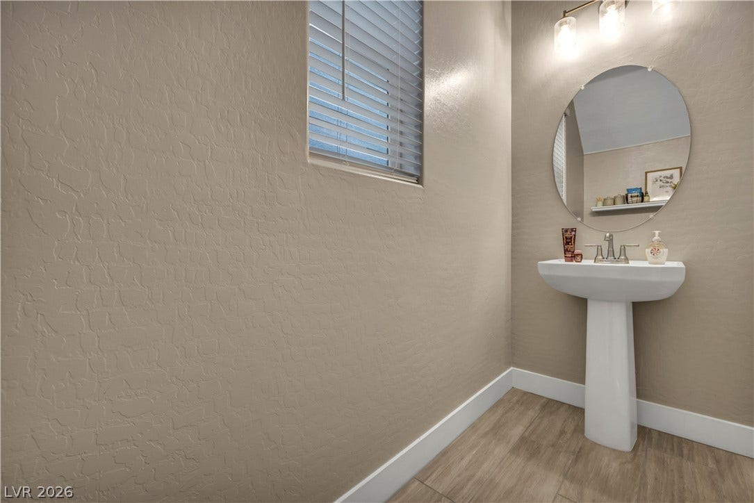 7128 Port Stephens Street, North Las Vegas, NV 89084 Smooth wood-look flooring and textured walls anchor this classic powder room setup.