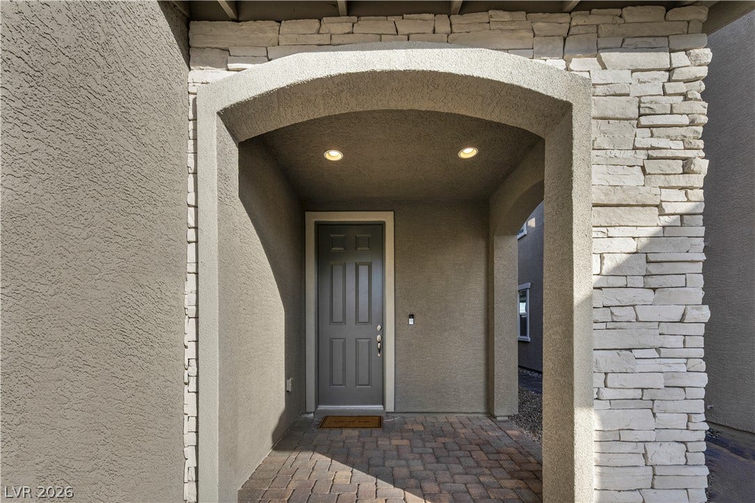 7128 Port Stephens Street, North Las Vegas, NV 89084 An arched covered entryway features textured stucco finishes, stone accents, and paved brick flooring.