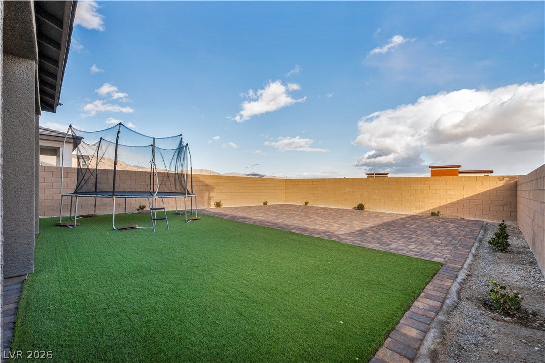 7128 Port Stephens Street, North Las Vegas, NV 89084 An enclosed backyard features manicured artificial turf alongside low-maintenance paver stones.