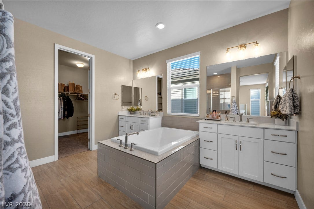 7128 Port Stephens Street, North Las Vegas, NV 89084 A spacious layout showcases a central soaking tub flanked by dual vanities under recessed lighting.