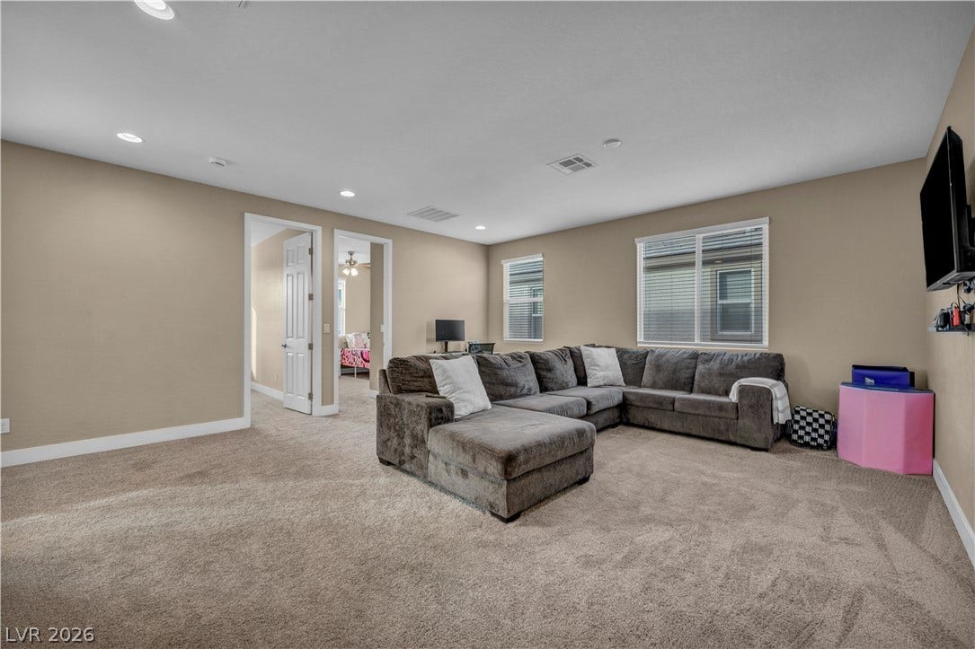 7128 Port Stephens Street, North Las Vegas, NV 89084 A spacious secondary living area features neutral walls, wall-to-wall carpeting, and recessed lighting.