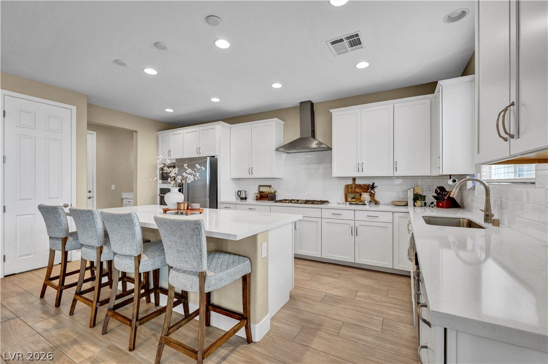 7128 Port Stephens Street, North Las Vegas, NV 89084 Streamlined cabinetry and sleek stone countertops define this modern, light-filled kitchen space.