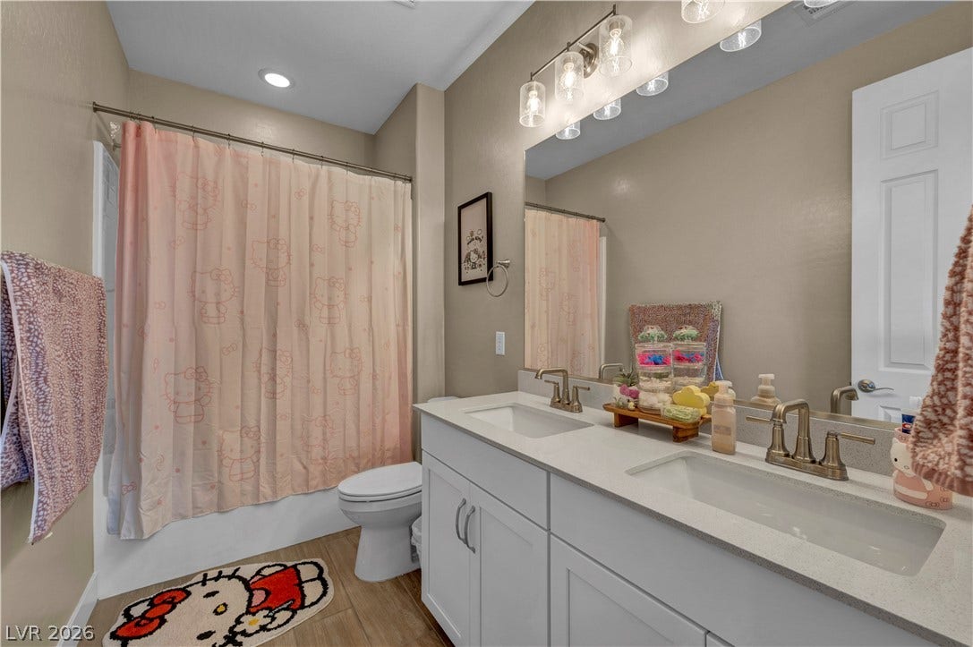 7128 Port Stephens Street, North Las Vegas, NV 89084 Double undermount sinks accent a stone-counter vanity adjacent to wood-look tile flooring.