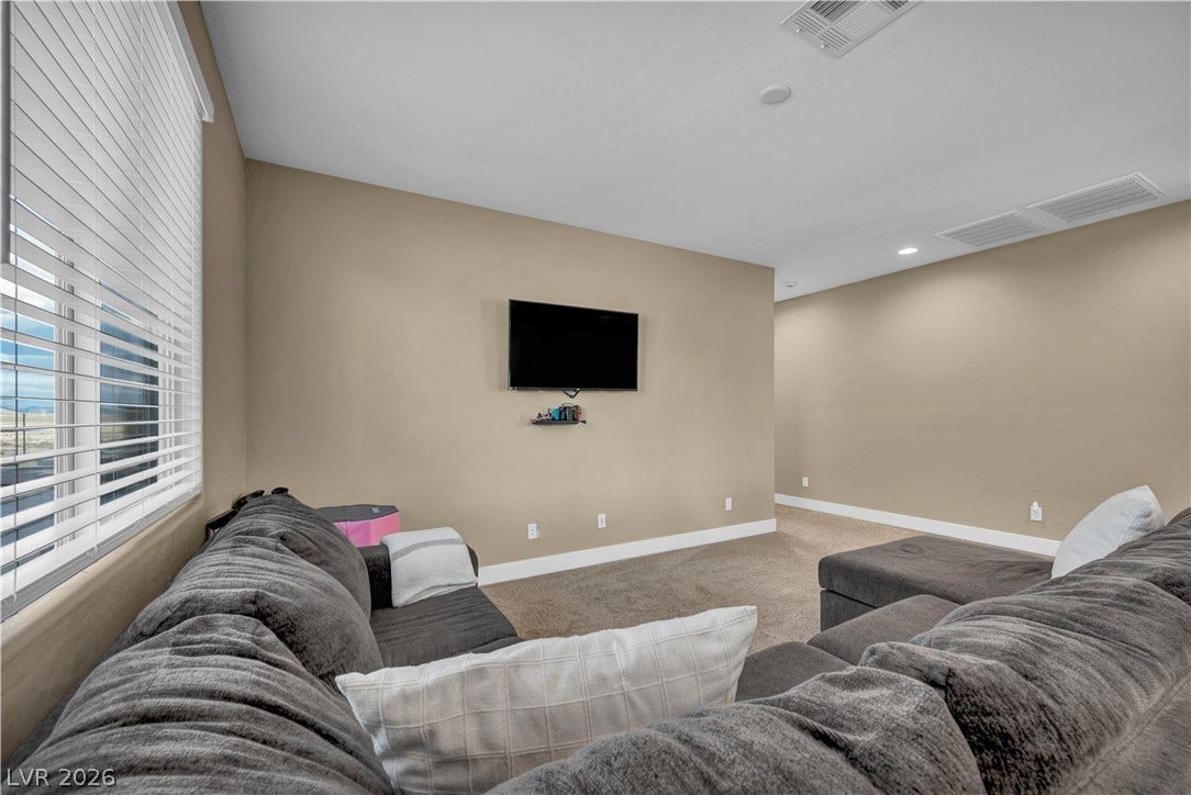 7128 Port Stephens Street, North Las Vegas, NV 89084 Smooth neutral walls and soft carpet ground this comfortable secondary living space.