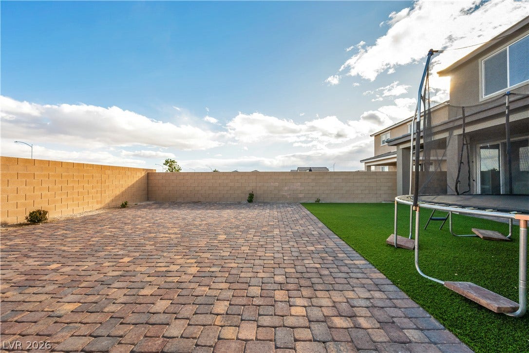 7128 Port Stephens Street, North Las Vegas, NV 89084 An expansive paved patio and green lawn sit enclosed within block wall fencing.
